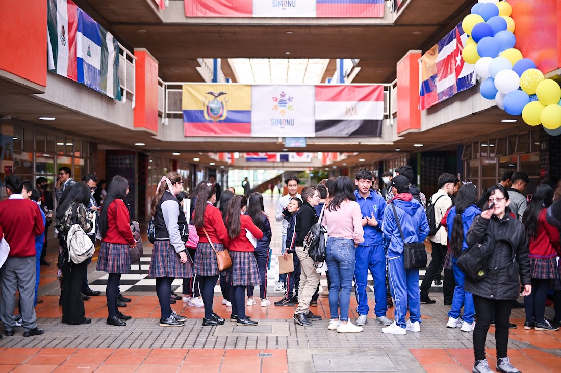 ‘Cambiamos tu vida, tú cambias el mundo’ fue el lema que este año entonaron los participantes en Simonu Bogotá-Región 2022, estrategia pedagógica y política que conmemoró una década, liderada por la Secretaría de Educación del Distrito (SED) y el Centro de Información de las Naciones Unidas para Colombia, Ecuador y Venezuela (CINU Bogotá), en el marco del Programa Integral de Educación Socioemocional, Ciudadana y Escuelas como Territorios de Paz.     Luego de seis meses de trabajo continuo en la selección de cargos de liderazgo, el sorteo de delegaciones y comisiones para colegios, los encuentros de formación, las asesorías, la elaboración de las guías de comisión, la articulación con entidades aliadas, entre otras acciones, se realizó la gran simulación de Naciones Unidas en el Colegio Ciudadela Educativa de Bosa, que ha sido anfitrión en ocho de las diez ediciones de Simonu.     Más de tres mil maestras, maestros, niñas, niños y jóvenes delegados y en cargos de liderazgo de 300 colegios y universidades de Bogotá, Cundinamarca, Meta, Tolima, Cartagena y Panamá hicieron parte de este ejercicio de liderazo. En forma presencial y en entornos virtuales debatieron y plantearon propuestas de solución sobre temas estratégicos para la ciudad, la región, Colombia y el mundo, haciendo especial énfasis en los Objetivos de Desarrollo Sostenible (ODS), a través de 114 comisiones tradicionales y especializadas.     Imagen dentro del texto 1     Además de potenciar la capacidad creativa e innovadora en la formulación de iniciativas de cambio desde los colegios, este año se reconocieron los logros de #Simonu10Años, identificando los momentos y aportes más significativos de esta experiencia de aprendizaje en nuevos liderazgos estudiantiles, diversidad, innovación en prácticas pedagógicas, creatividad, pensamiento crítico y trabajo en equipo. Conozca aquí sus opiniones.     Conversando sobre la simulación     “Estoy muy emocionada porque hace 10 años estaba aquí en este colegio donde inició Simonu, mostrando que era posible, desd