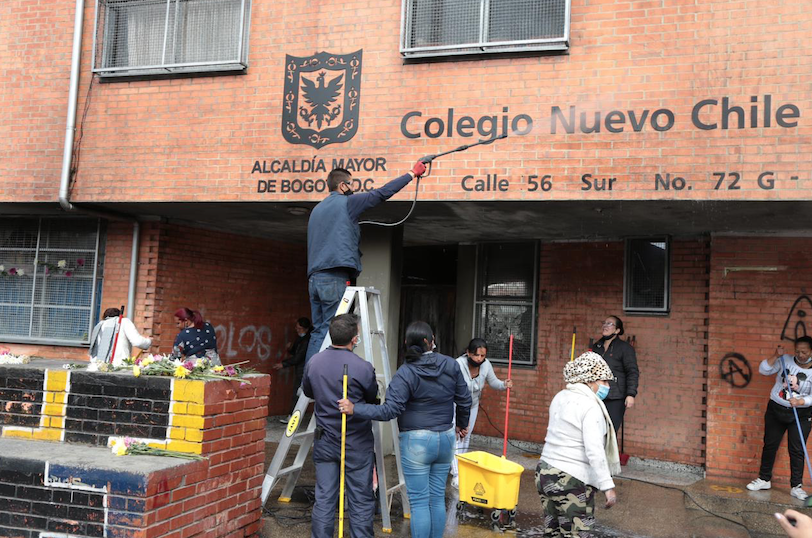 Hombre limpiando fachada quemada del colegio nuevo Chile