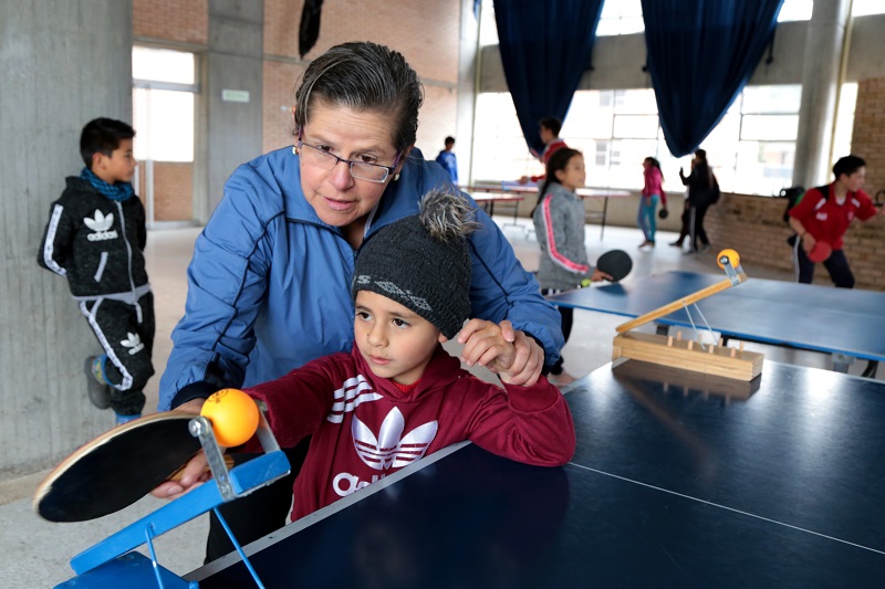 Una profesora con un estudiante en una mesa de tenis